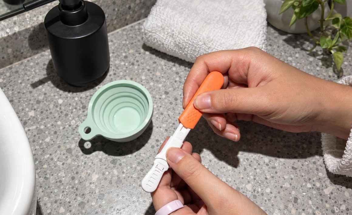Hand uncapping an Ultra4 test wand next to the silicone cup
